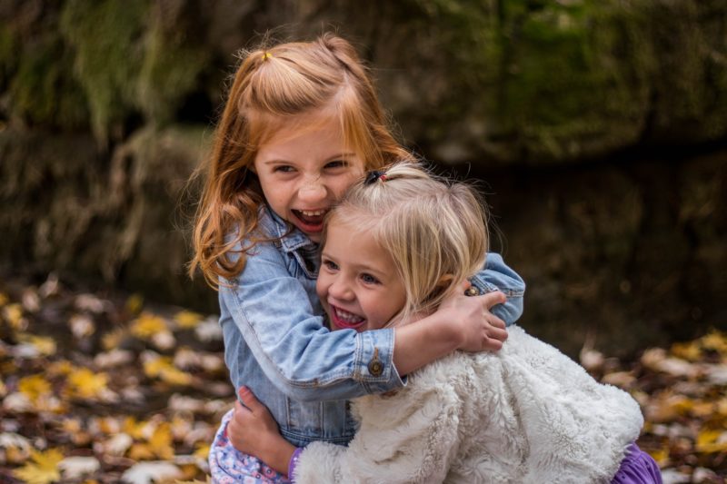 two small girls hugging outside