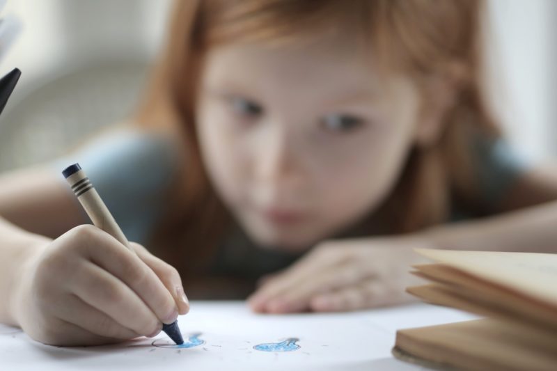 small girl drawing with crayon