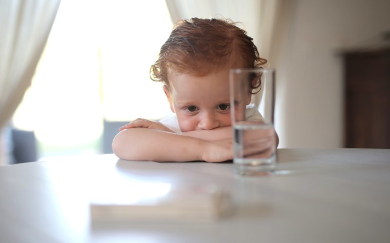 small boy at table looking at glass