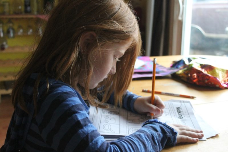 small girl writing with pencil